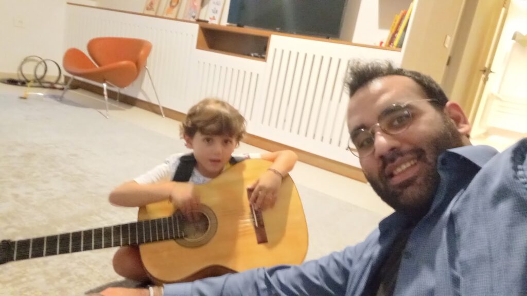 Elias taking a selfie with a young student holding a classical guitar