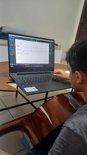 Un élève suit un cours de guitare en ligne sur un ordinateur portable