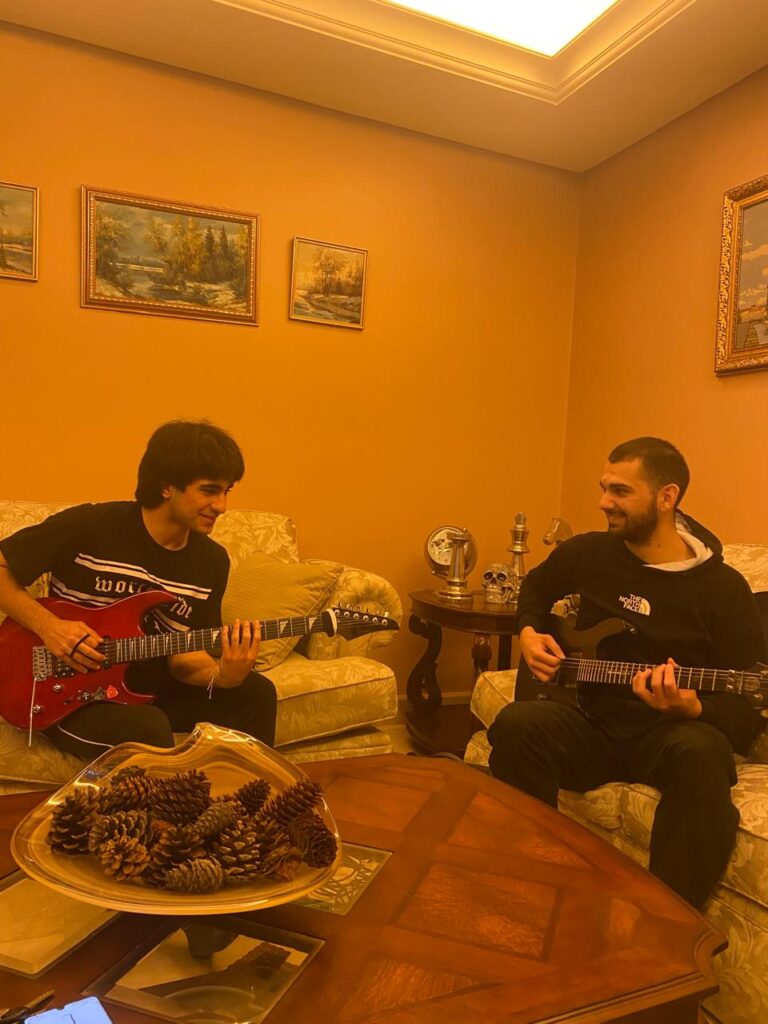 A teacher and a student playing electric guitars in a living room