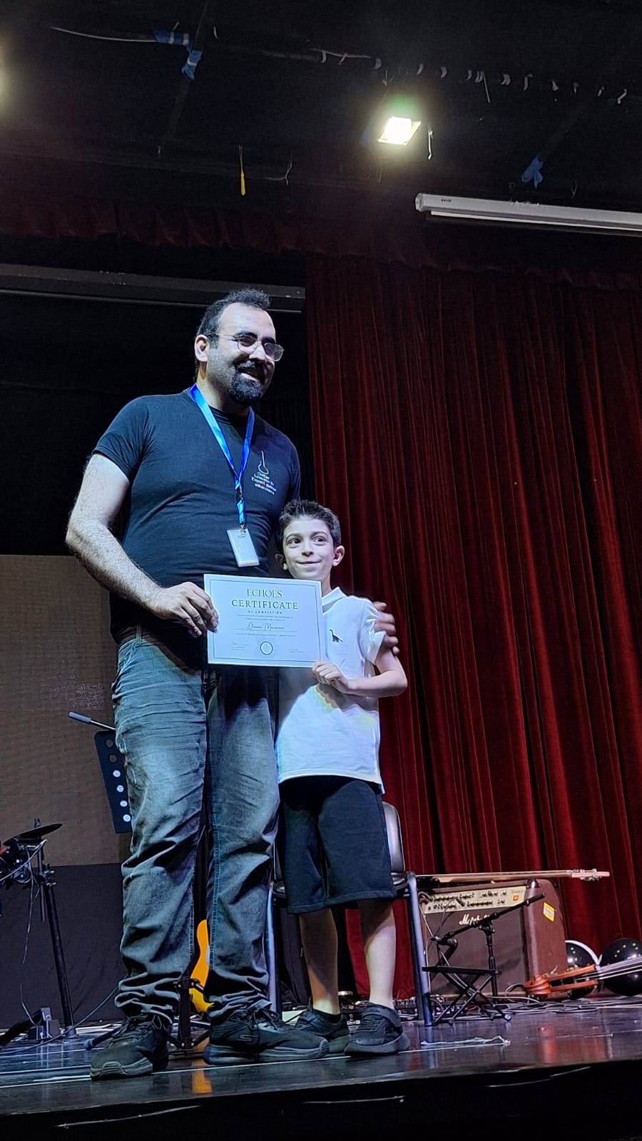 Elias on the Echoes stage with a young student holding his certificate