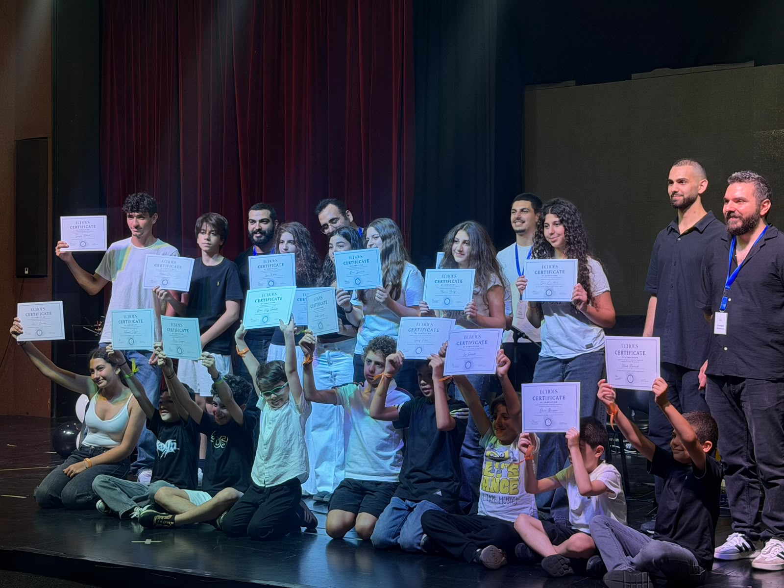 Students and teachers celebrating on stage with their certificates after Echoes