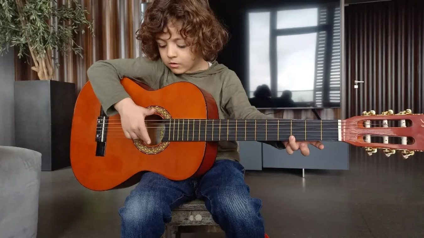 A young student practising classical guitar at home