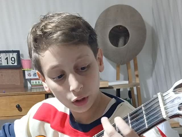 Un garçon travaille la guitare classique à la maison