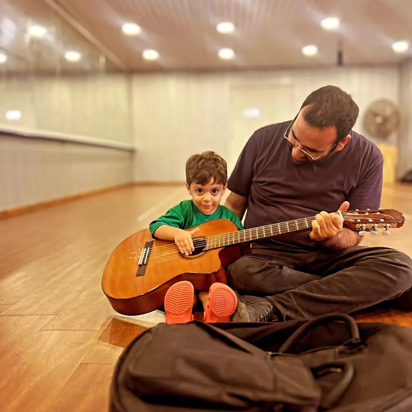 Elias showing a small child how to hold the guitar
